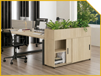 Light wood desk with built-in storage and planters in a bright modern office, with a computer monitor and rolling chair nearby.