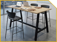 Collaborative office desk with two black stools, laptops and notebooks on a wooden table in a modern workspace.