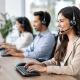 Mobiliario call center para equipos que rinden | OfficeDeco Three customer service agents wearing headsets work at computers in a bright office setting.